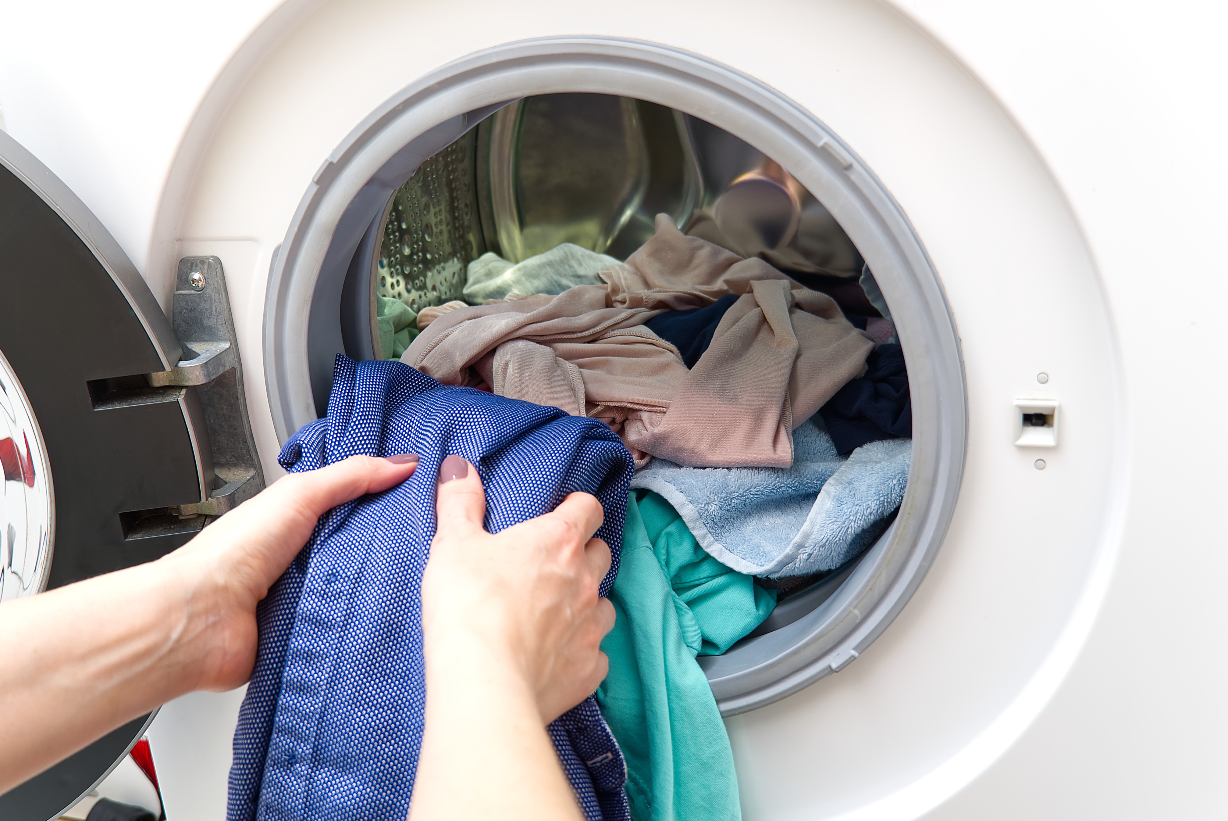 The image shows a person taking out clothes of a washer.