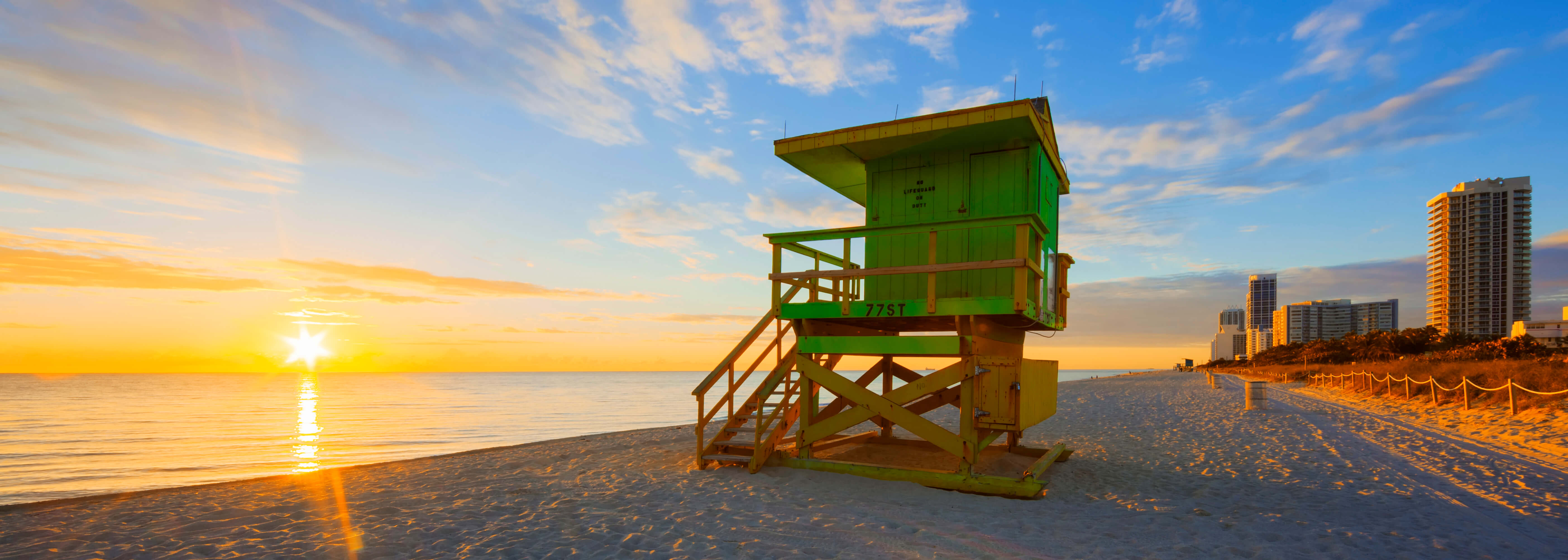 The image shows a scenic sunrise view of the coastline of a beach in South Miami. 