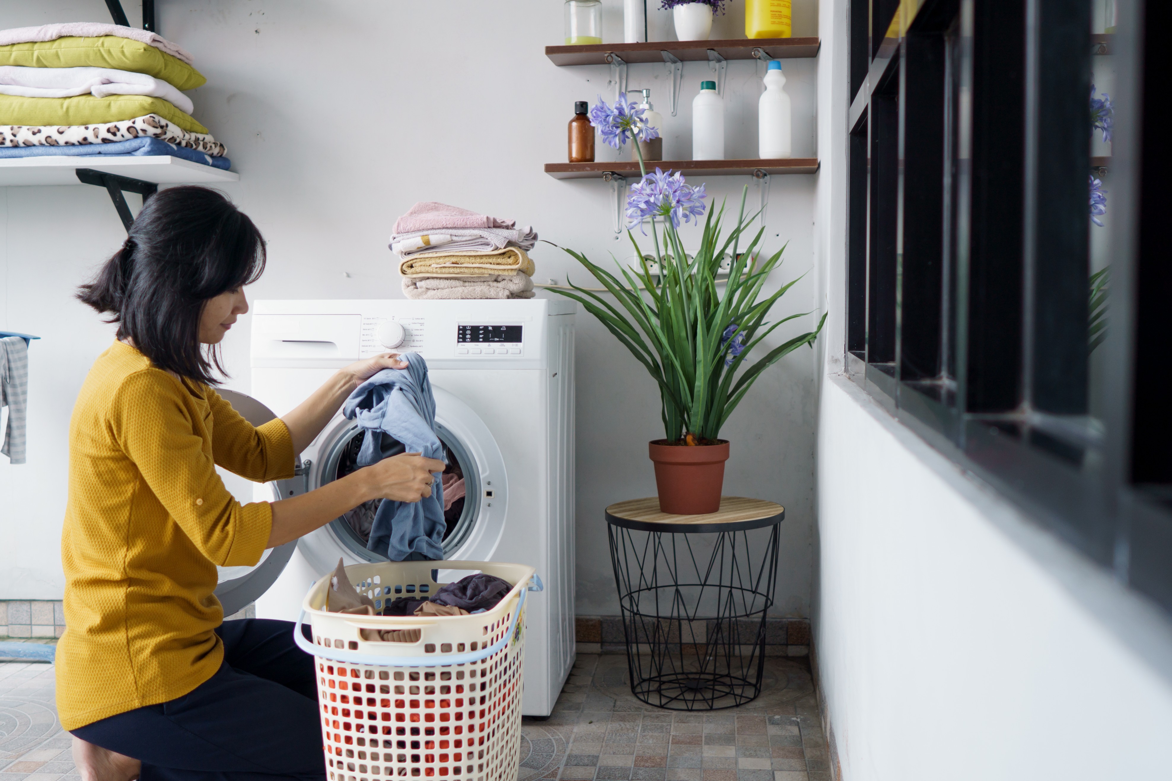 The image shows a woman in front of a washing machine doing laundry. 
